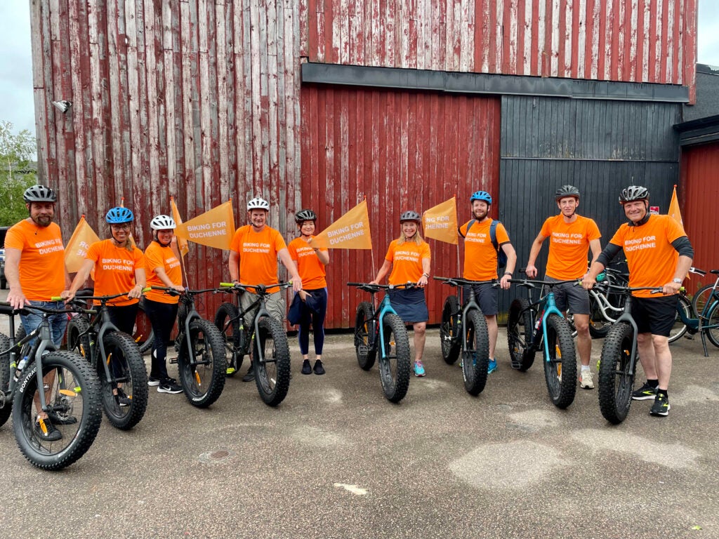 PTC's Northern Europe team in orange shirts, standing with their bikes, preparing for the De Duchenne 40